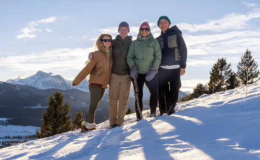 Family portrait on snowy hillside together in sunshine