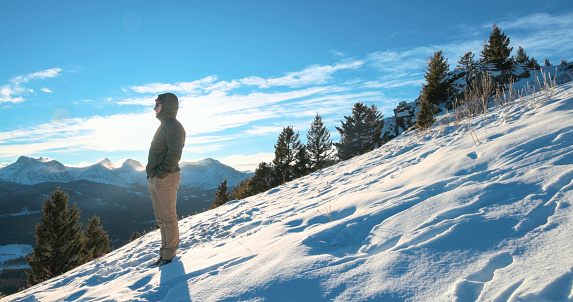 Young man pauses on snowy hill and looks out