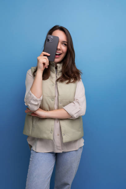 istock brunette young woman holding a smartphone in her hands on a studio background 1910805650