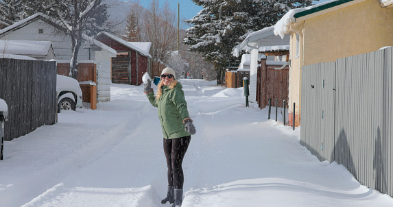 Mature woman throws snowball on a snowy winter day
