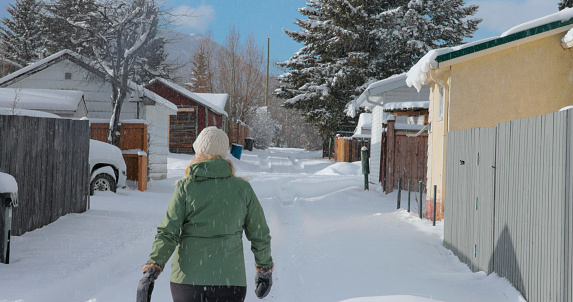Mature woman walks down alley on a snowy winter day