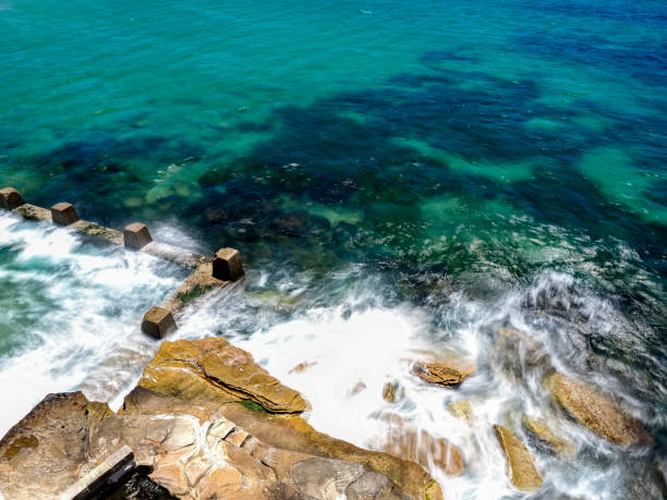istock Powerful white swirling waves (blurred motion) crashing into rocky coastline 1910819905