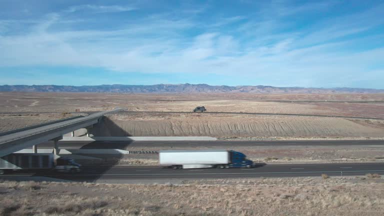 A Drone Shot of Two Semi Trucks with Passing by on I-70 in Utah on a Sunny Winter Day