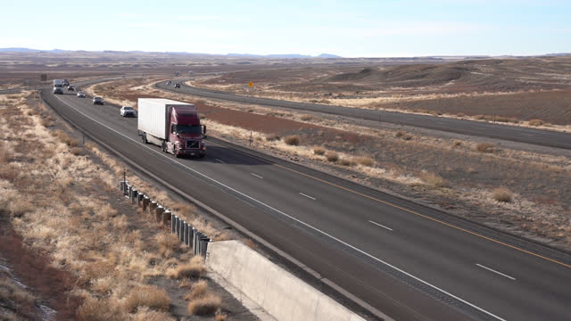 Handheld Shot of a Semi Truck with a Perfect White Trailer Passing by on a Two Lane Highway