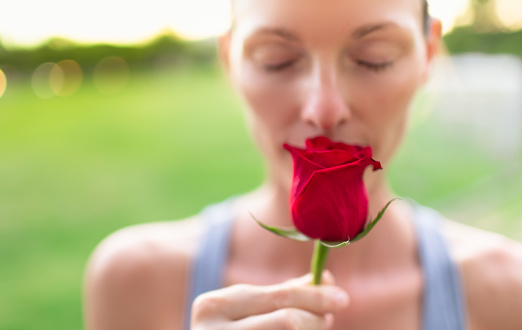 Women smelling beautiful red rose.