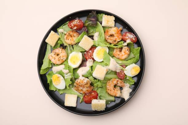 istock Delicious Caesar salad with shrimps on beige table, top view 1910859495