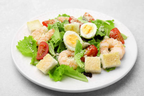 istock Delicious Caesar salad with shrimps on light table, closeup 1910863655