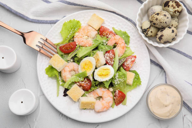 istock Delicious Caesar salad with shrimps and fork served on white textured table, flat lay 1910864159