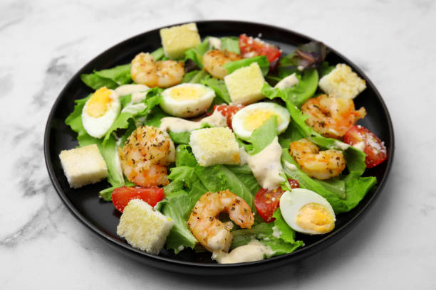 istock Delicious Caesar salad with shrimps on white marble table, closeup 1910865712
