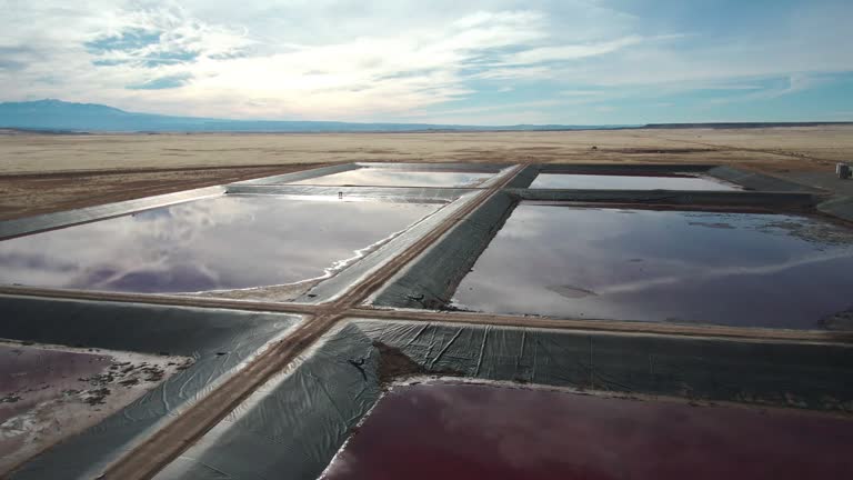 Drone Shot of a Oilfield Water Retention Ponds in Eastern Utah Near Thompson Springs on a Sunny Winter Day with The Dramatic Sky Reflecting in the Water