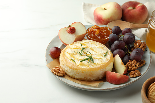 Tasty baked brie cheese served on white marble table. Space for text