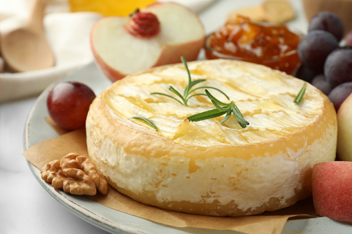 Tasty baked brie cheese served on table, closeup