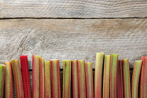 Fresh rhubarb stalks on wooden table, top view. Space for text
