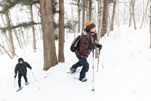 A man and woman enjoying snowshoeing in a winter mountain forest.