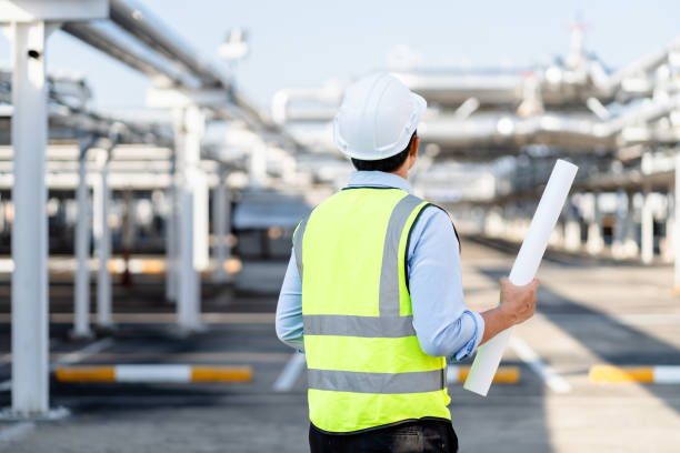 istock Electrical engineers holding blueprints looking confident with a factory plant background, contractor inspection constructed on-site, Solar power station site and architecture concept. 1910904110