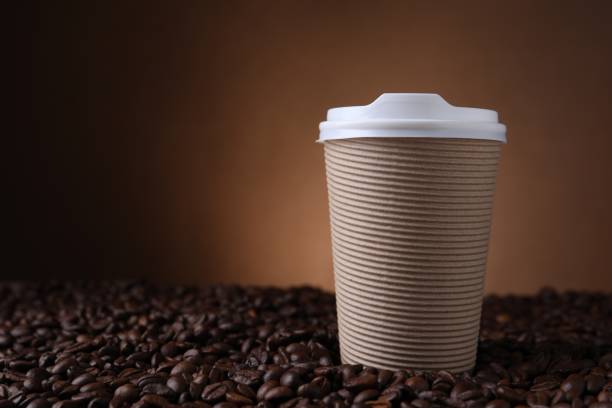 A takeaway coffee with sugar and stirrer in shot.