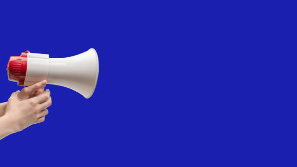 istock Megaphone in woman hands on a blue background. 1910914228
