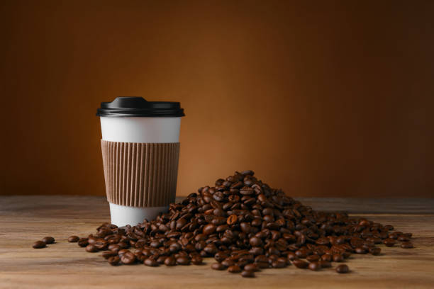 istock Coffee to go. Paper cup and roasted beans on wooden table, space for text 1910915897