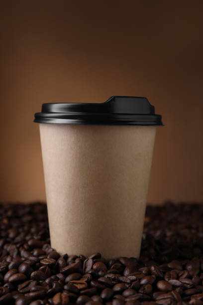 istock Coffee to go. Paper cup on roasted beans against brown background 1910915908