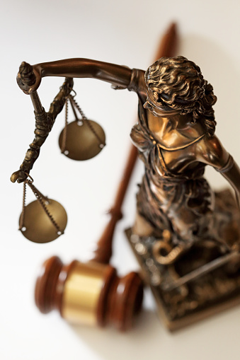 Lady justice stands over gavel.