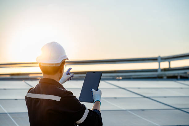 istock Engineer electrician using a digital tablet to check solar panels on the roof, clean energy power nature, photovoltaic systems, the energy produced by the sun, sustainable business concept. 1910921135
