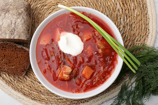 Tasty borscht with sour cream served on white table, flat lay