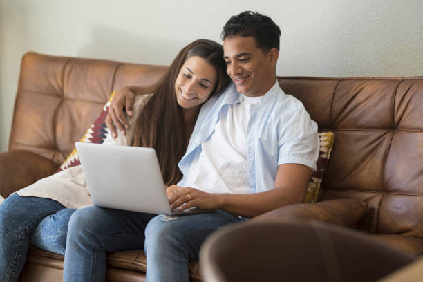 istock Young couple moving to a new home relaxing sitting on the sofa using computer laptop, smiling happy for moving to new apartment 1910936679