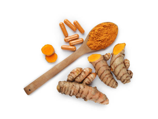 istock Spoon with aromatic turmeric powder, pills and raw roots isolated on white, top view 1910941759