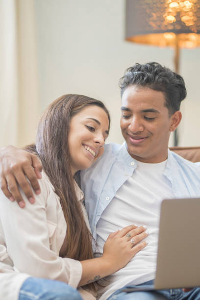 istock Young couple moving to a new home relaxing sitting on the sofa using computer laptop, smiling happy for moving to new apartment 1910942306