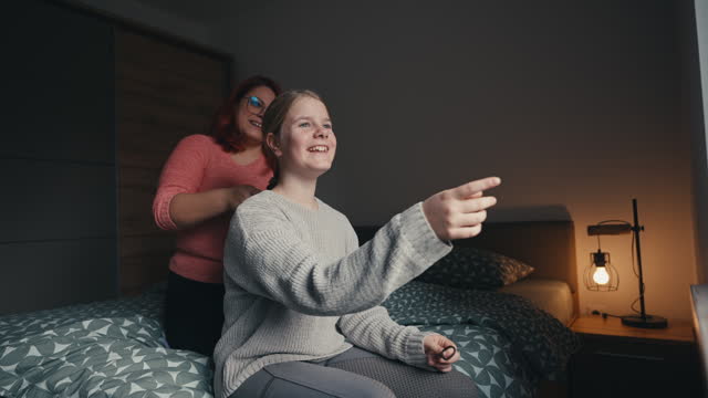 SLO MO Cheerful Mid Adult Mother Braiding Daughter's Hair on Bed in Bedroom at Night
