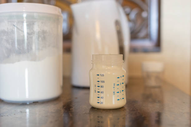 istock Preparing baby bottle of powdered milk on table 1911006795