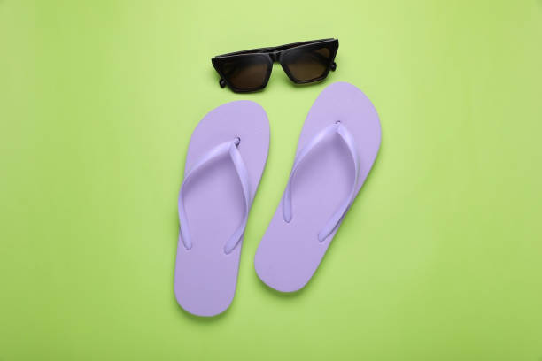 istock Stylish flip flops and sunglasses on light green background, flat lay 1911019398