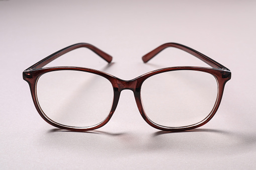 Stylish pair of glasses on light background, closeup