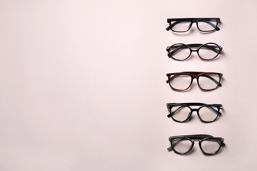 Many different stylish glasses on light grey background, flat lay. Space for text