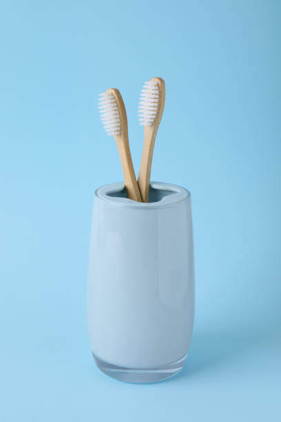 istock Bamboo toothbrushes in holder on light blue background 1911035783