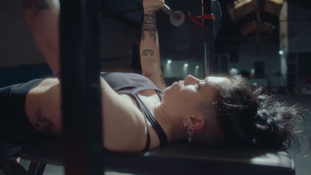 Female Athlete Doing Barbell Bench Press during Workout in Gym