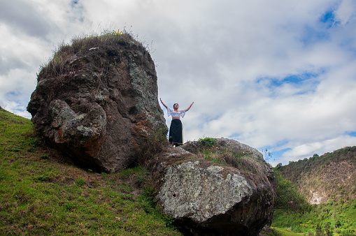 copyspace of panoramic landscape of ecuador with two big rocks where an indian woman imbues mother nature under the white clouds. earth day. High quality photo