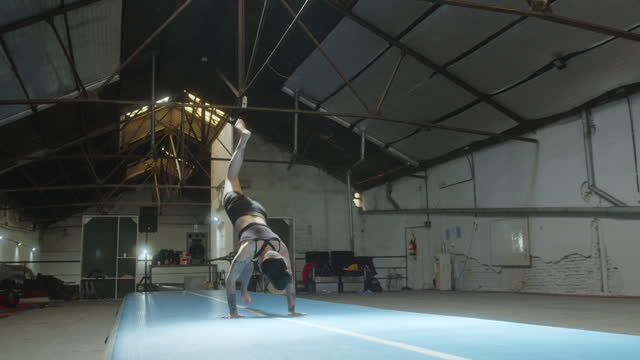Female Gymnast Practicing Headstand and Backflip on Mat in a Gym