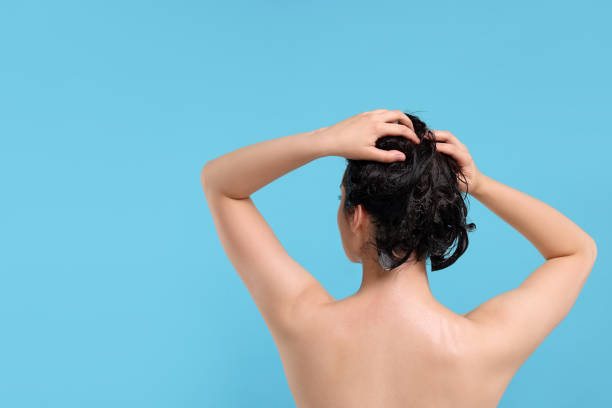 istock Woman washing hair on light blue background, back view. Space for text 1911101799