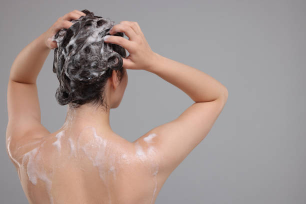 istock Woman washing hair on grey background, back view. Space for text 1911104424