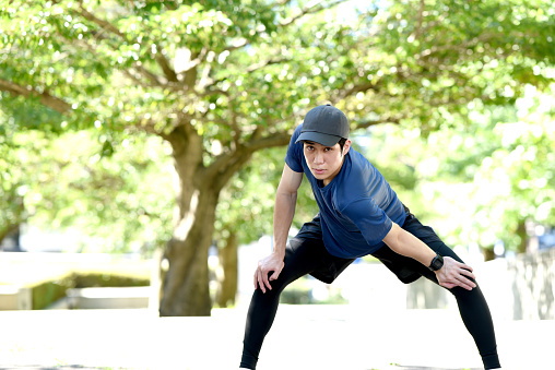 Young Asian man wearing sportswear doing warm-up exercises outdoors