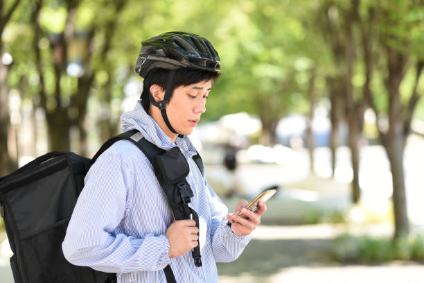 istock A young Asian man carrying a backpack provides a delivery service on his bicycle and searches for a delivery address on his smartphone. 1911146300