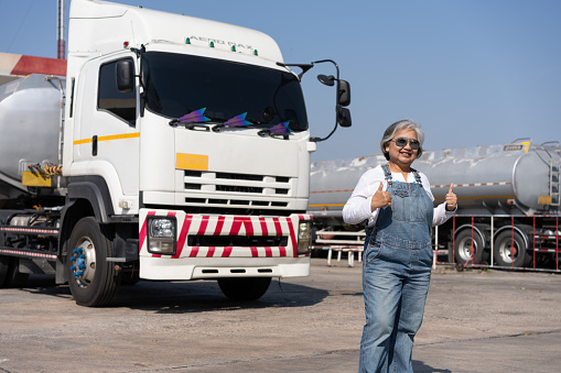 Business owner standing in front of oil truck after performing a pre-trip inspection on a truck. Concept of preventive maintenance.