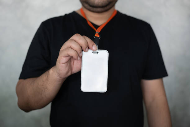 Male hand showing blank white badge on grey background