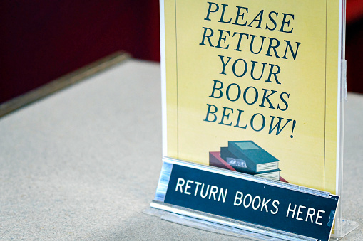 Book return sign in a library with negative space to the left.