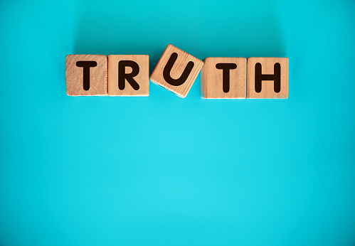 TRUTH word made with toy blocks on blue background.
