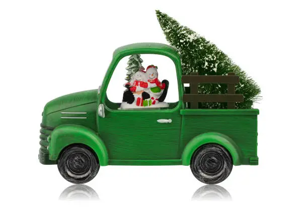 Photo of A New Year's toy, Christmas decoration for the house in the form of a green car with snowmen and a Christmas tree, isolated on a white background