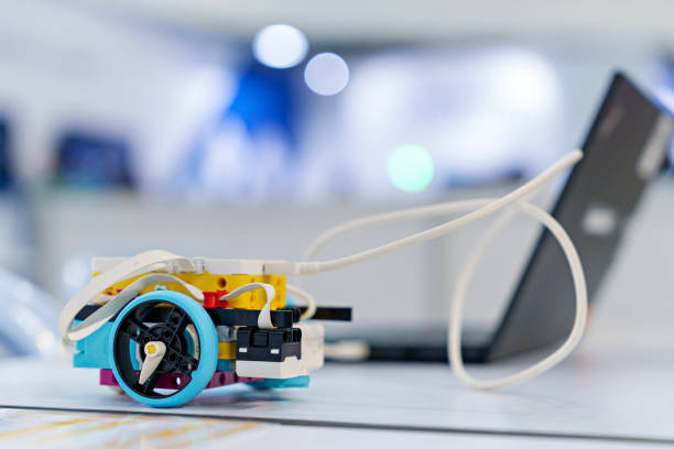 In a science project, a close-up view of a DIY robotic car on working desk background captures the essence of coding, technology, robotics, and science. This image represents the exciting intersection of these fields, showcasing innovation and the future of technology.