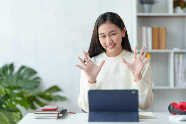 istock Beautiful young Asian woman college student is video chatting with her classmates using laptop, smiling faces and gestures happily studying. 1911393734