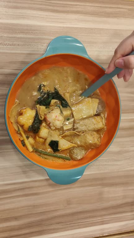 Unrecognizable woman eating laksa Singapore